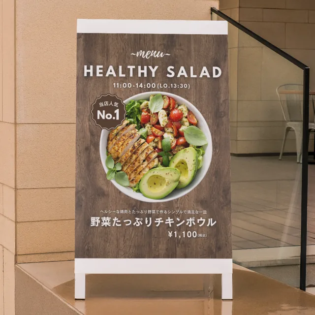 キッチンカーの A 型看板メニュー。「HEALTHY SALAD」の見出しと、野菜たっぷりチキンボウルの写真